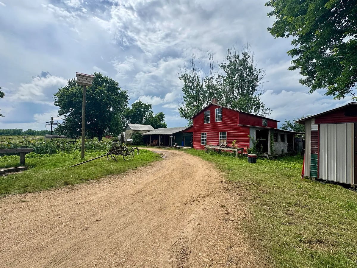 Dirt lane past red Amish shop building with purple martin house, Randolph Mississippi