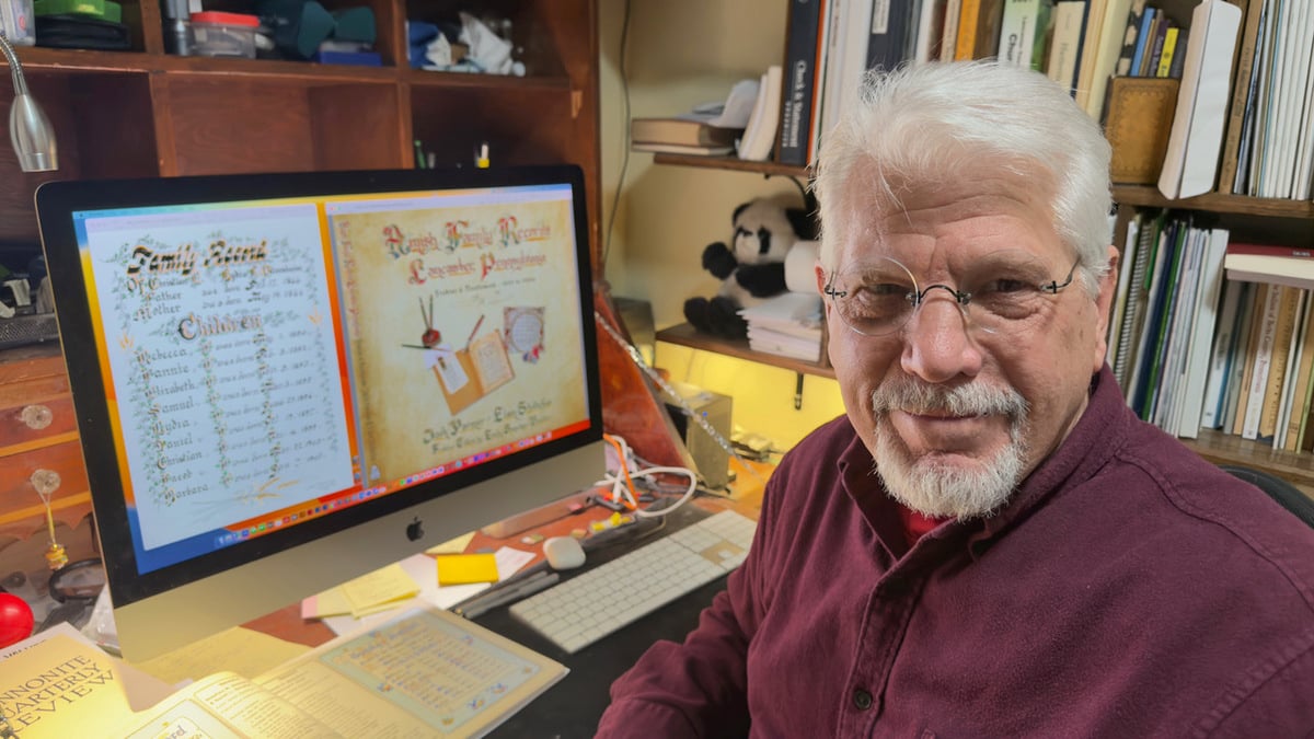 Elam Stoltzfus at his desk with the book