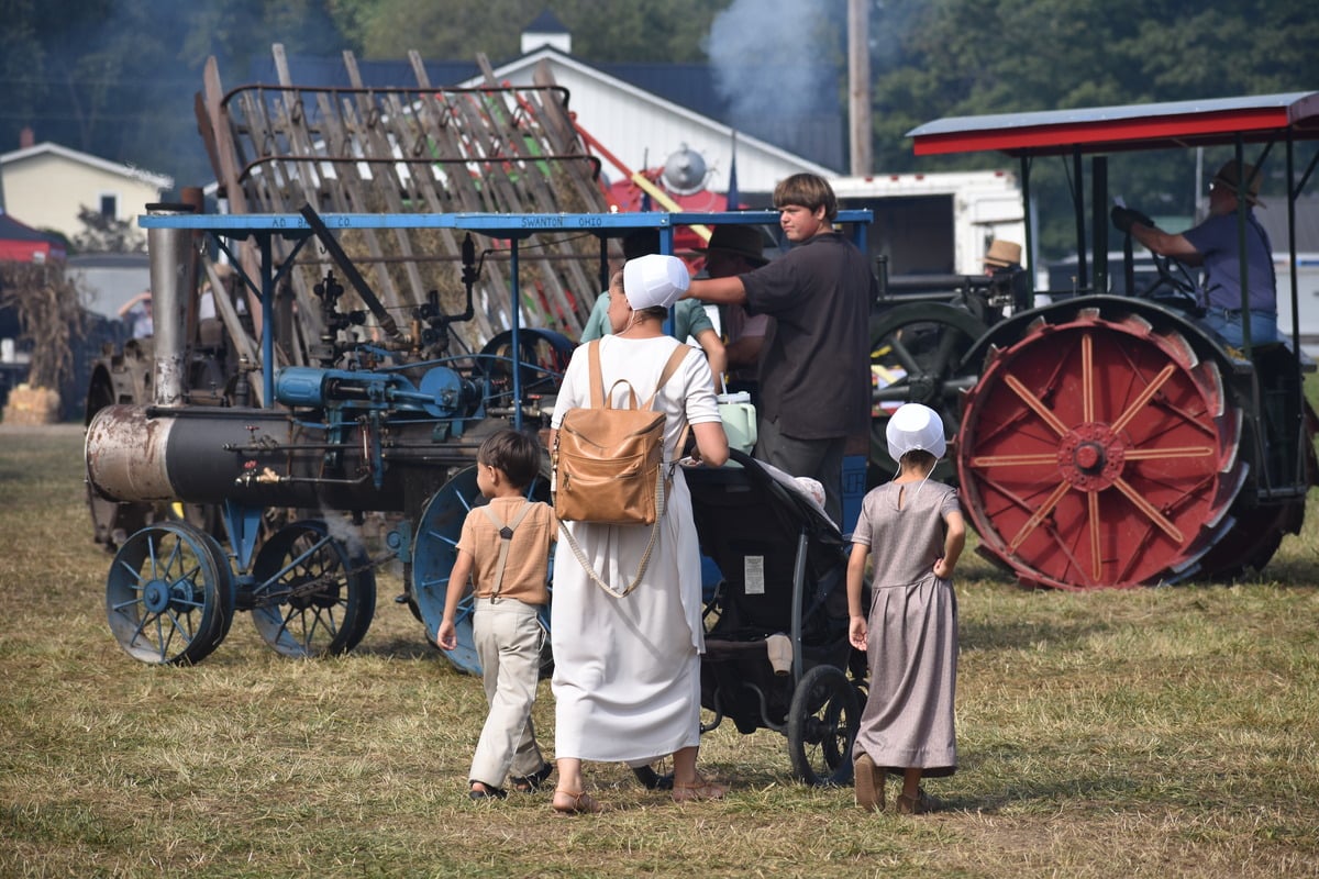 Amish mother and children walk past an A.D. Baker steam engine at Rentown Old Fashion Days