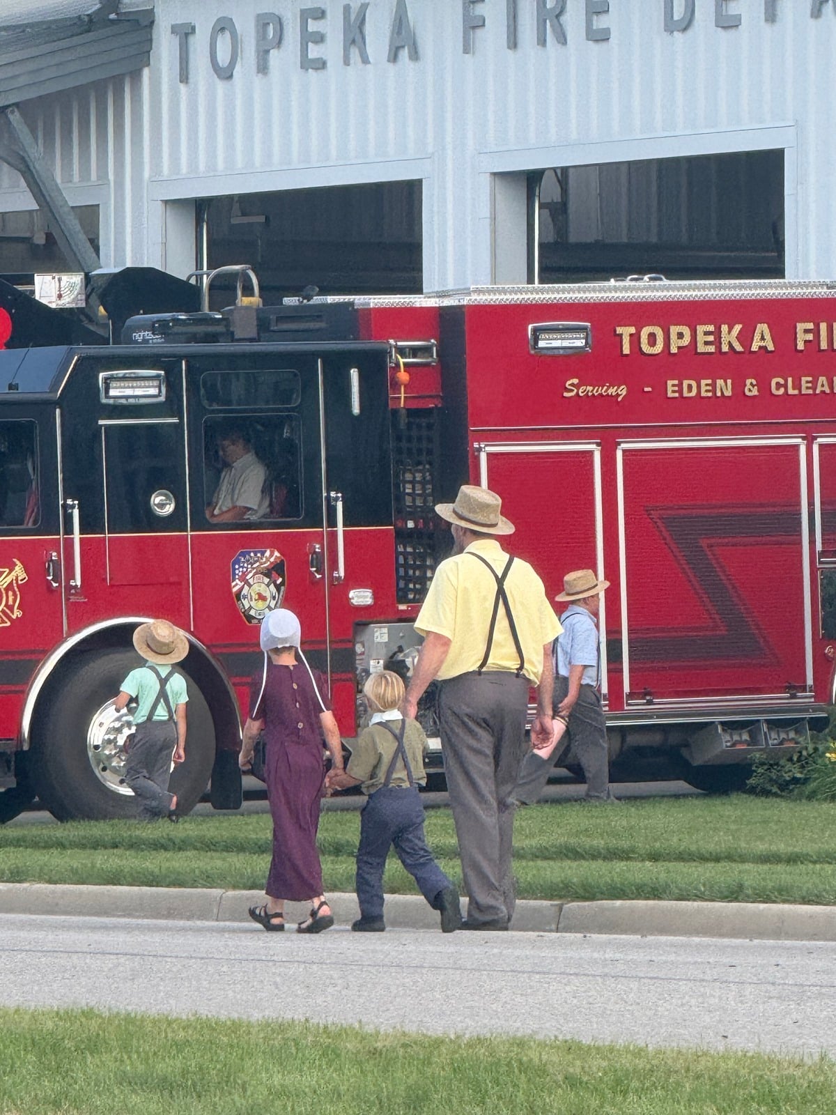 Amish man walking with children toward a Topeka fire truck