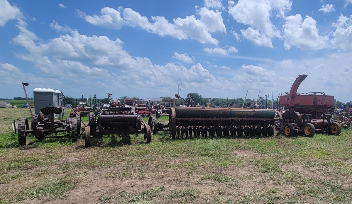 A row of farm equipment including an Oliver Superior grain drill at the auction