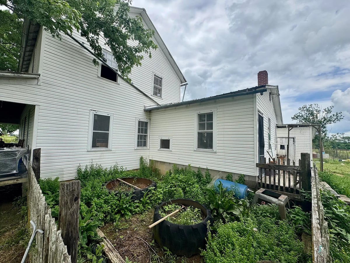 Fenced garden with tire planters beside a white Amish farmhouse in Randolph, Mississippi