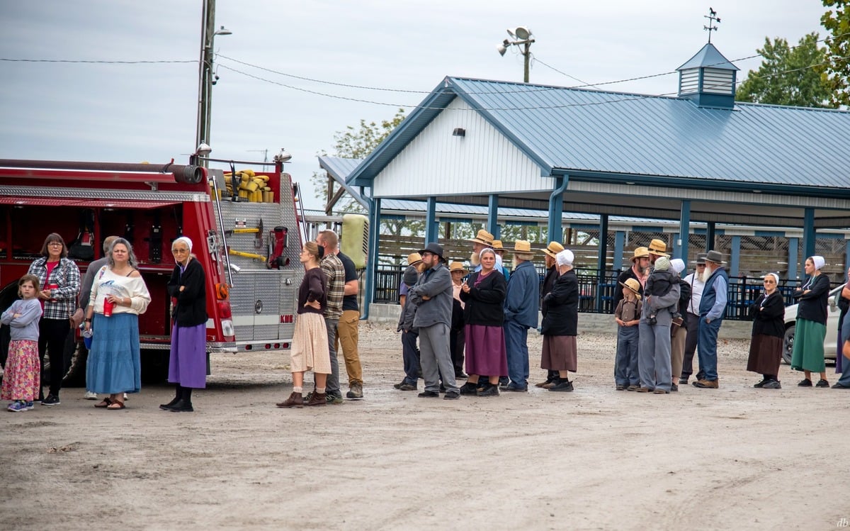 Amish and non-Amish waiting in line beside a fire truck