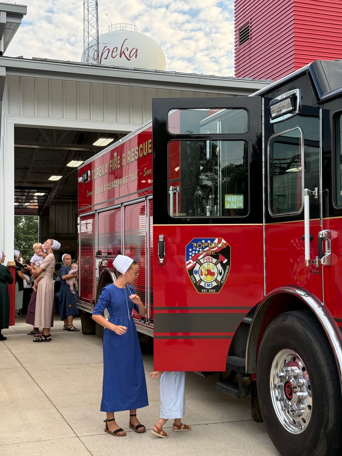 Amish girl beside an open fire engine door at the Topeka Fire Department