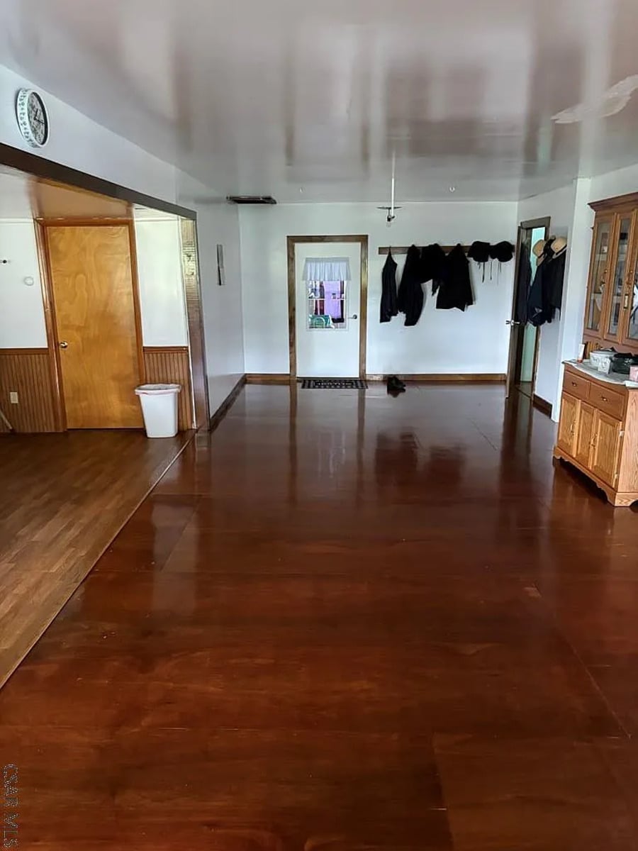 Amish coats and hats hanging on hooks in a hallway with a glossy floor