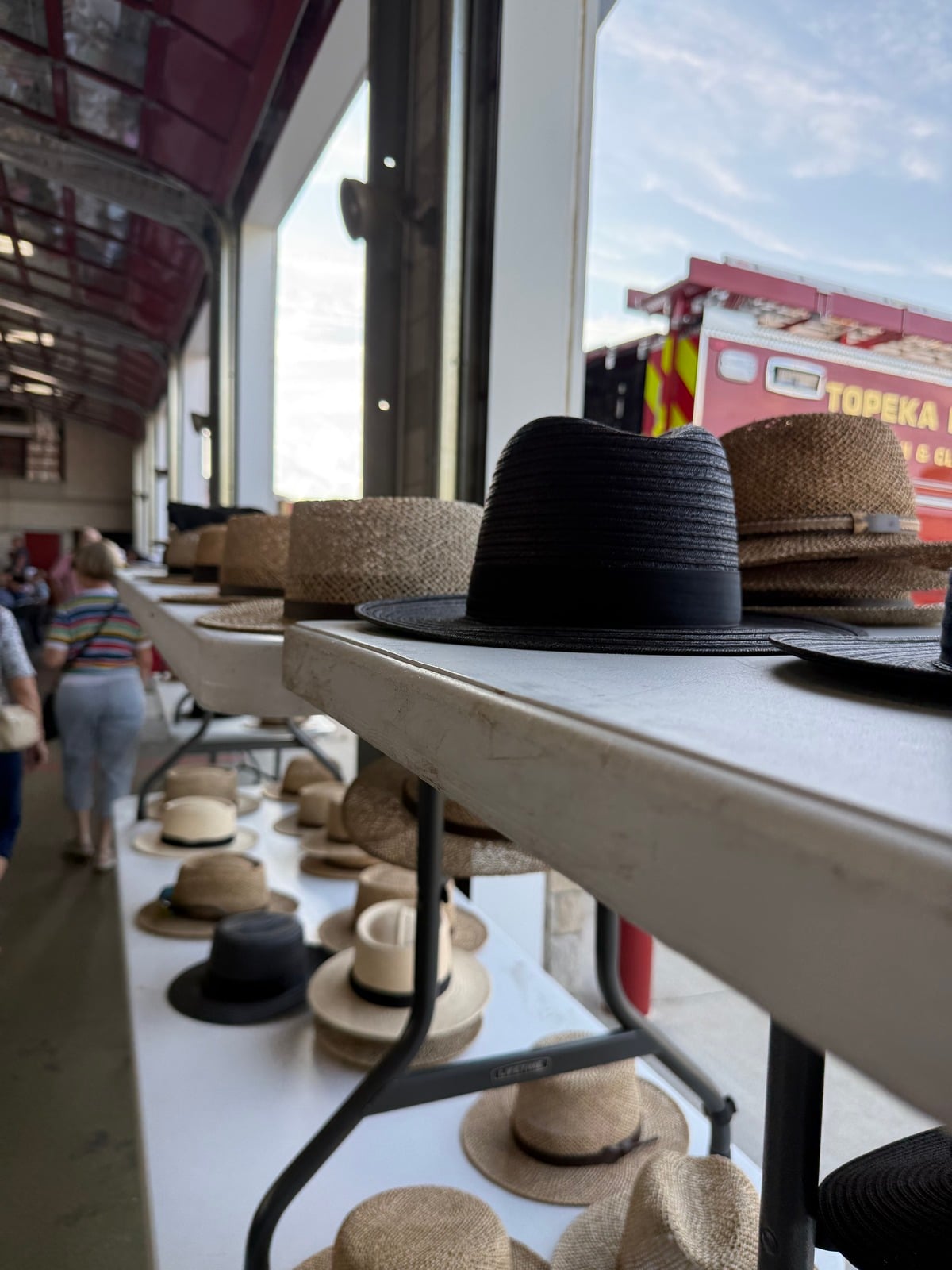 Amish straw and black hats lined up on folding tables at the fire station