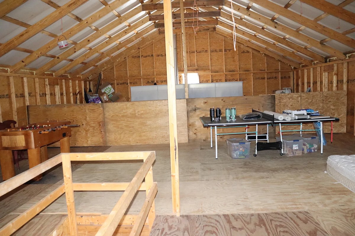 Angled view of the unfinished upstairs showing the stovepipe, plywood knee walls, and game area