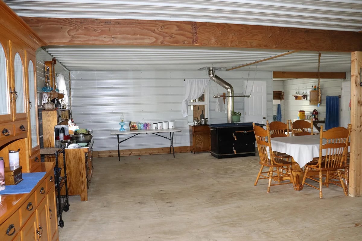 Amish dining area with oak hutch, oil lamps on a wall shelf, and a long table