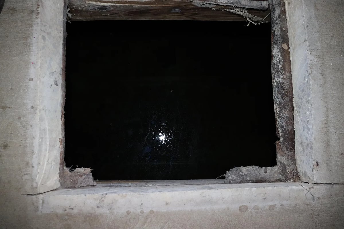 Looking straight down into the dark opening beneath the pantry trapdoor
