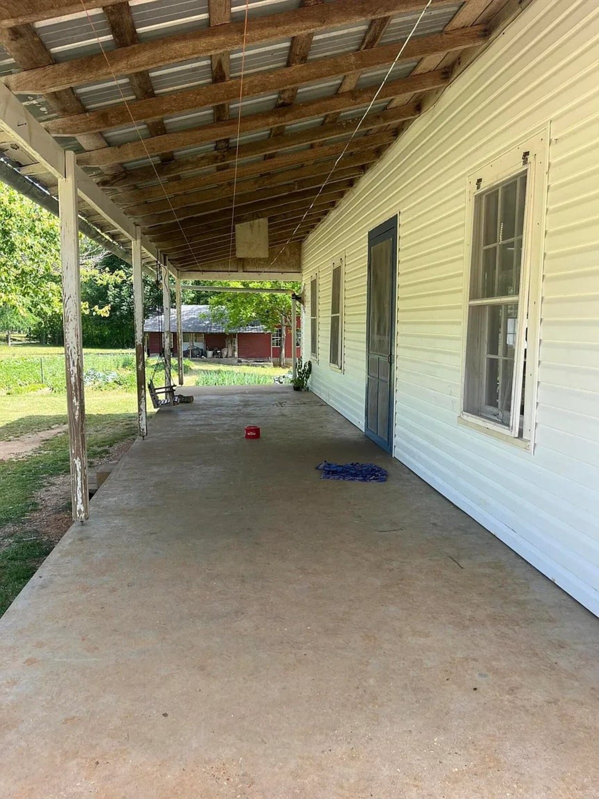 Long covered concrete porch with exposed beam ceiling and interior clothesline, Amish home in Randolph Mississippi