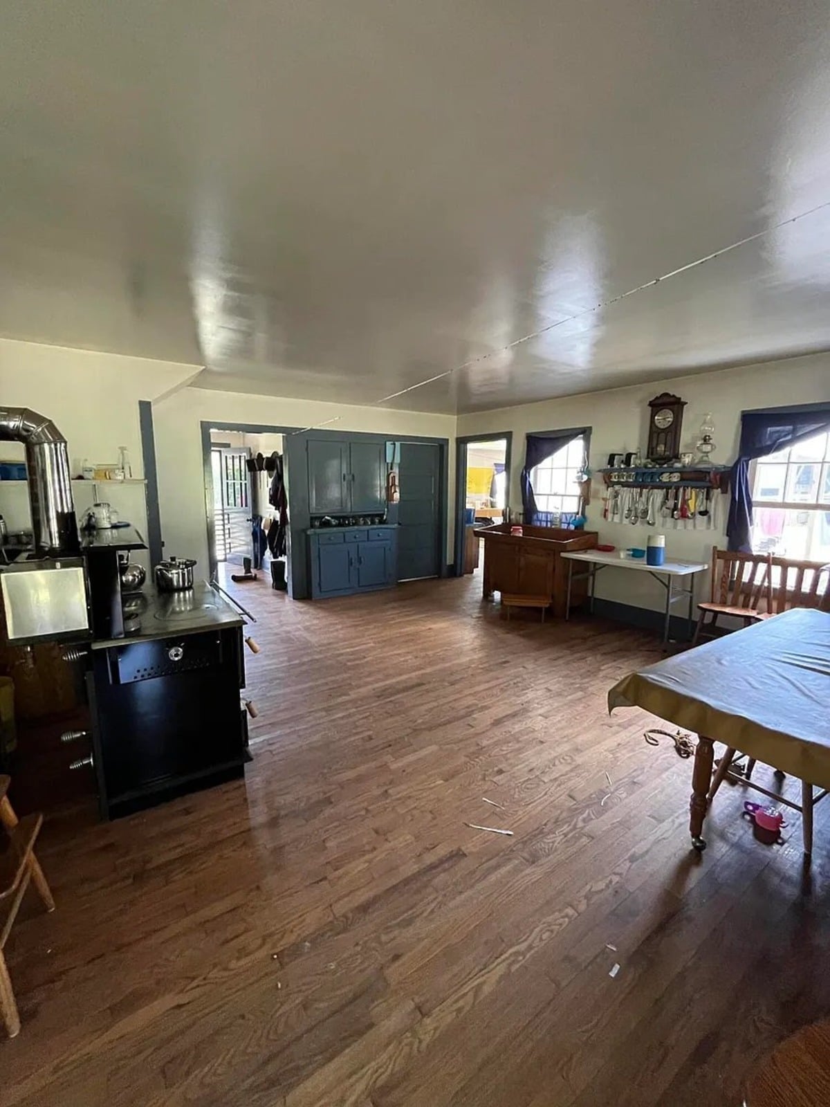 Amish kitchen with black wood cookstove, blue painted cabinet, wall clock, and large dining table, Randolph Mississippi