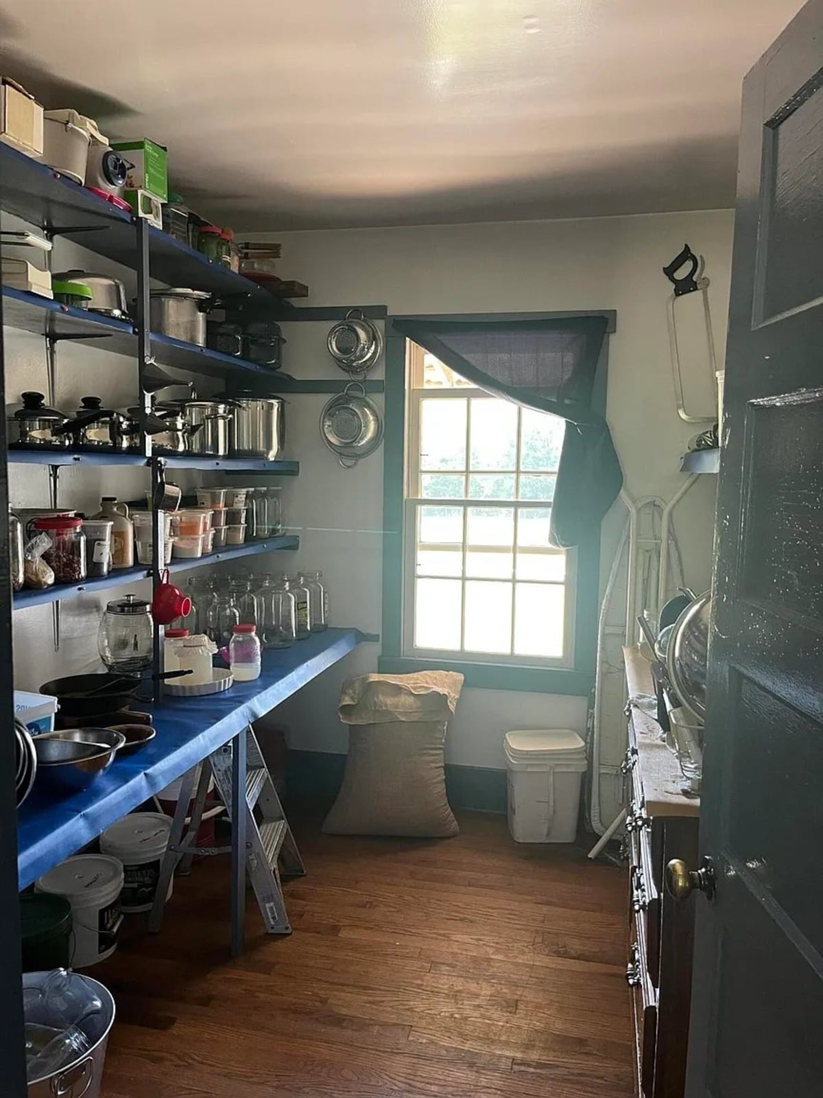 Amish pantry with shelves of mason jars, metal cookware, grain sacks, and hand pump, Randolph Mississippi
