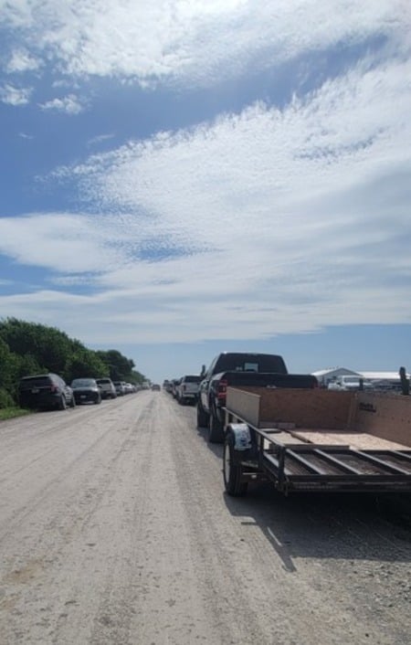 Vehicles and trailers parked along a dirt road at the Jamesport auction