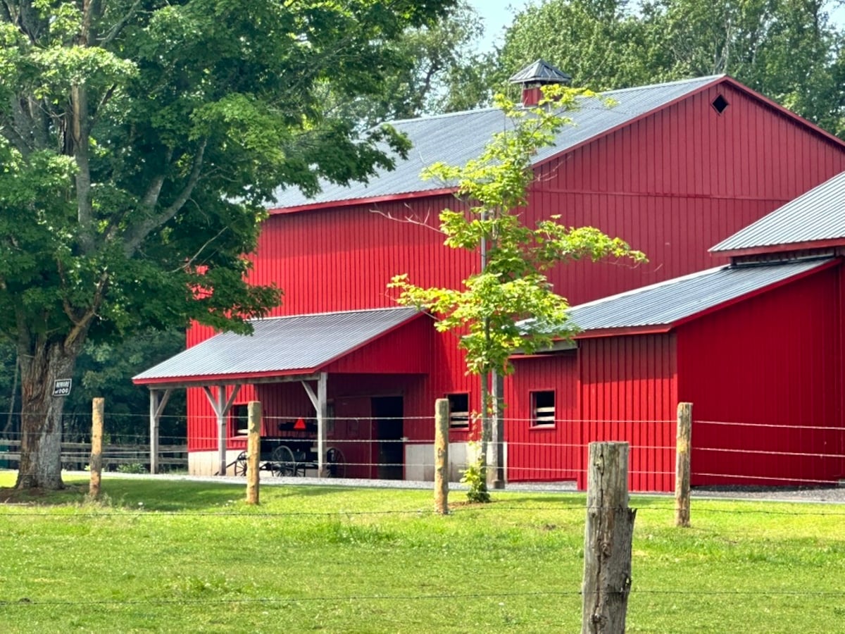 A large red Amish barn with buggy parked underneath open overhang, Prince Edward Island, Canada