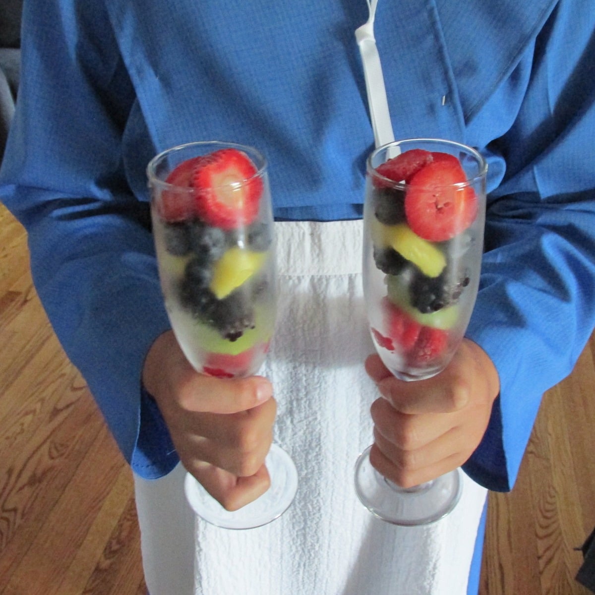 Amish wedding server in a blue dress and white apron holding two fruit cups