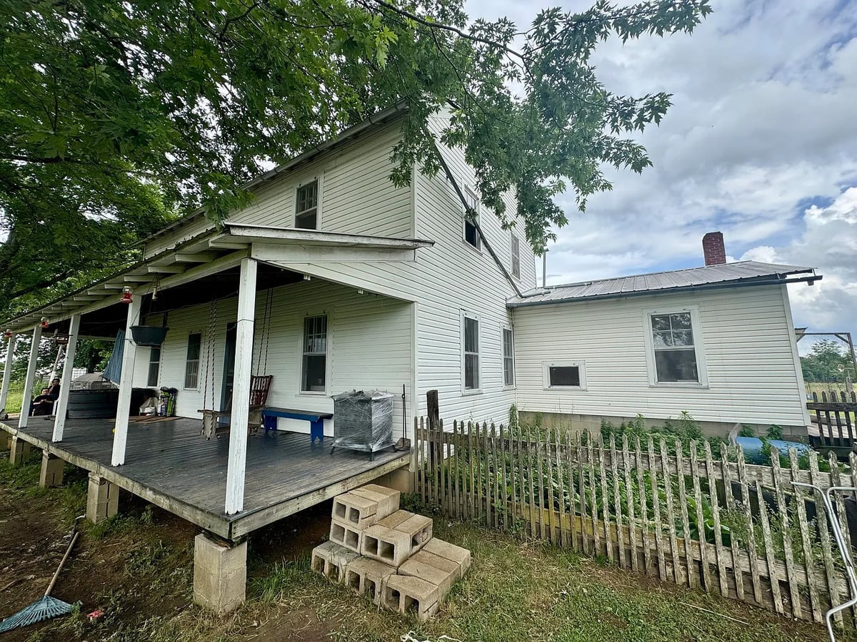 Side porch with porch swing and picket-fenced garden on an Amish farmhouse in Randolph, Mississippi
