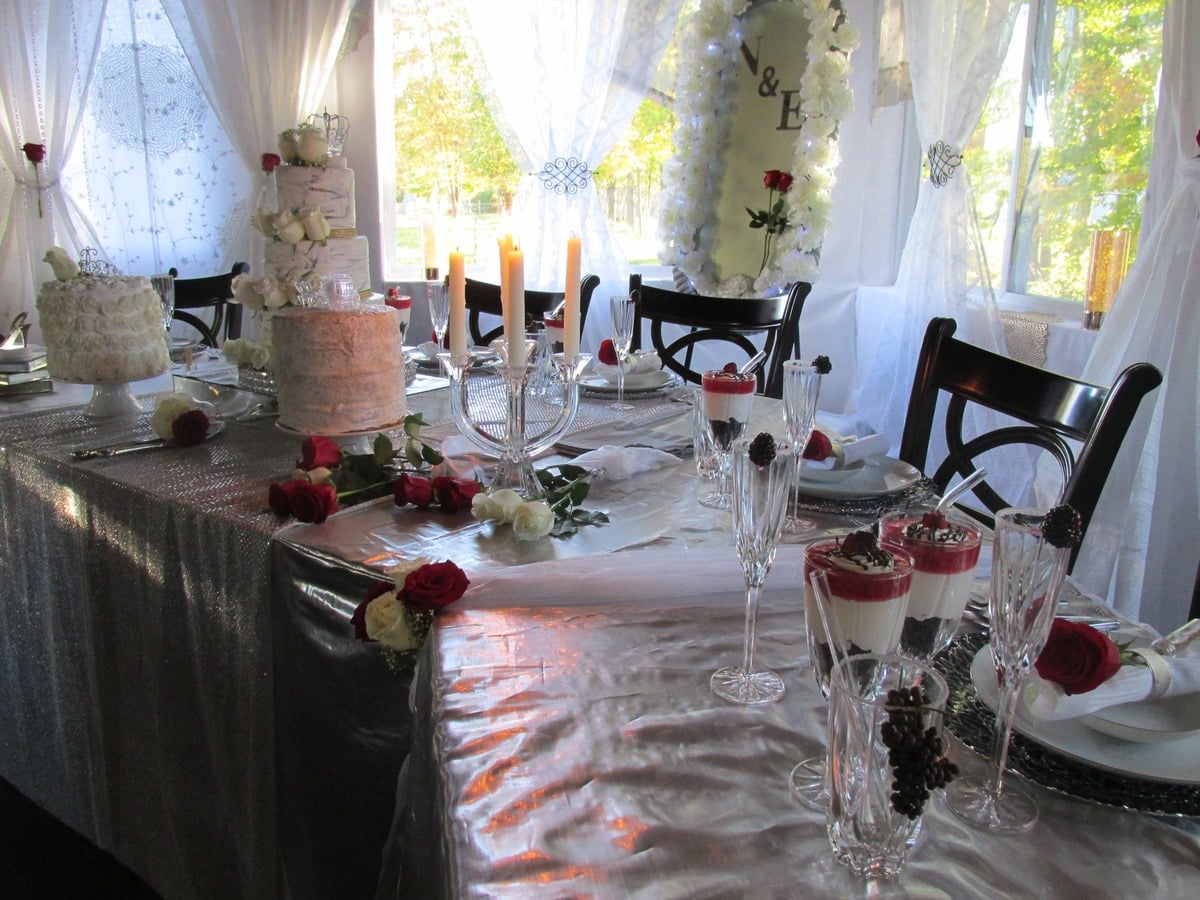 Silver and red bridal corner at an Amish wedding with candles and cakes