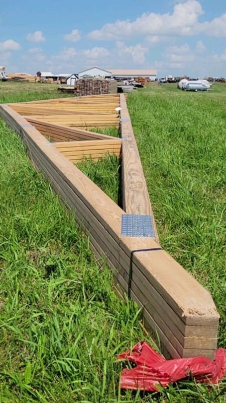 Stacked prefabricated wooden roof trusses in the grass at the auction