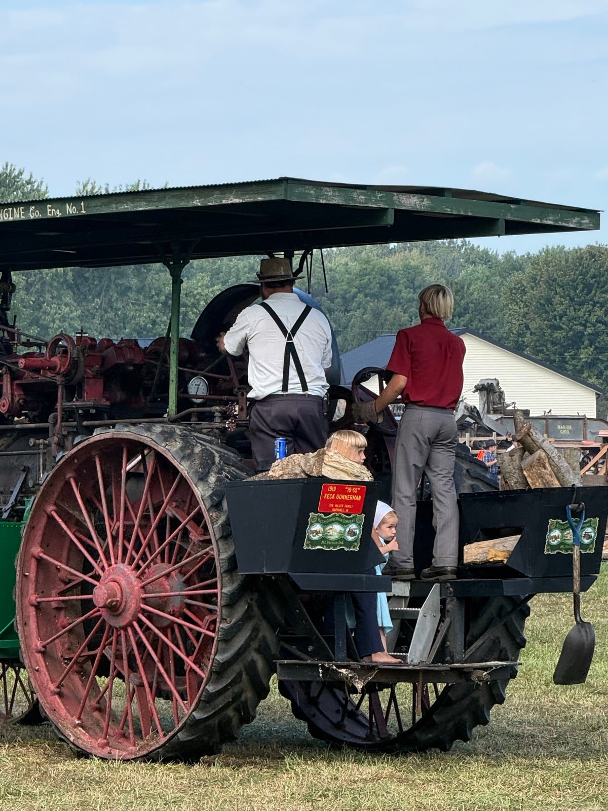 Young Amish girl peeks out from the back of a 1919 Keck Gonnerman steam engine