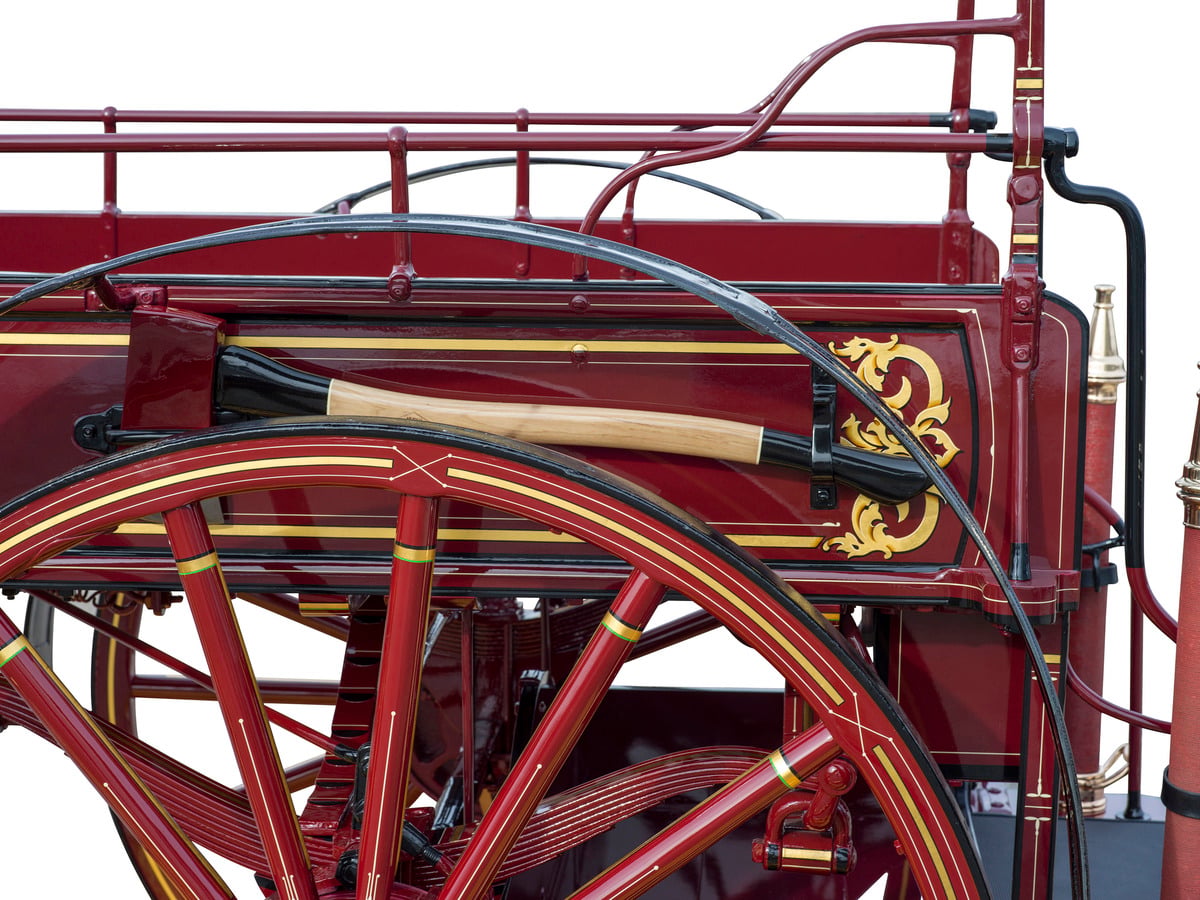 Close view of gold leaf scrollwork, pinstriping and a mounted axe on a restored fire wagon