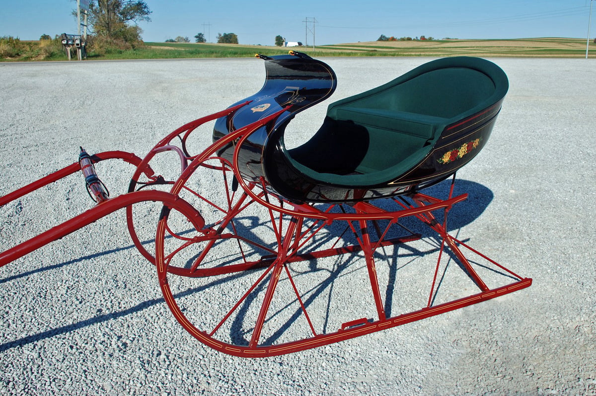 Fully restored black sleigh with red runners and green upholstery