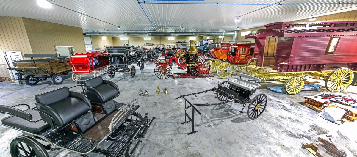 Wide view of the Weaver Wagons shop floor filled with wagons, carriages and a steam pumper