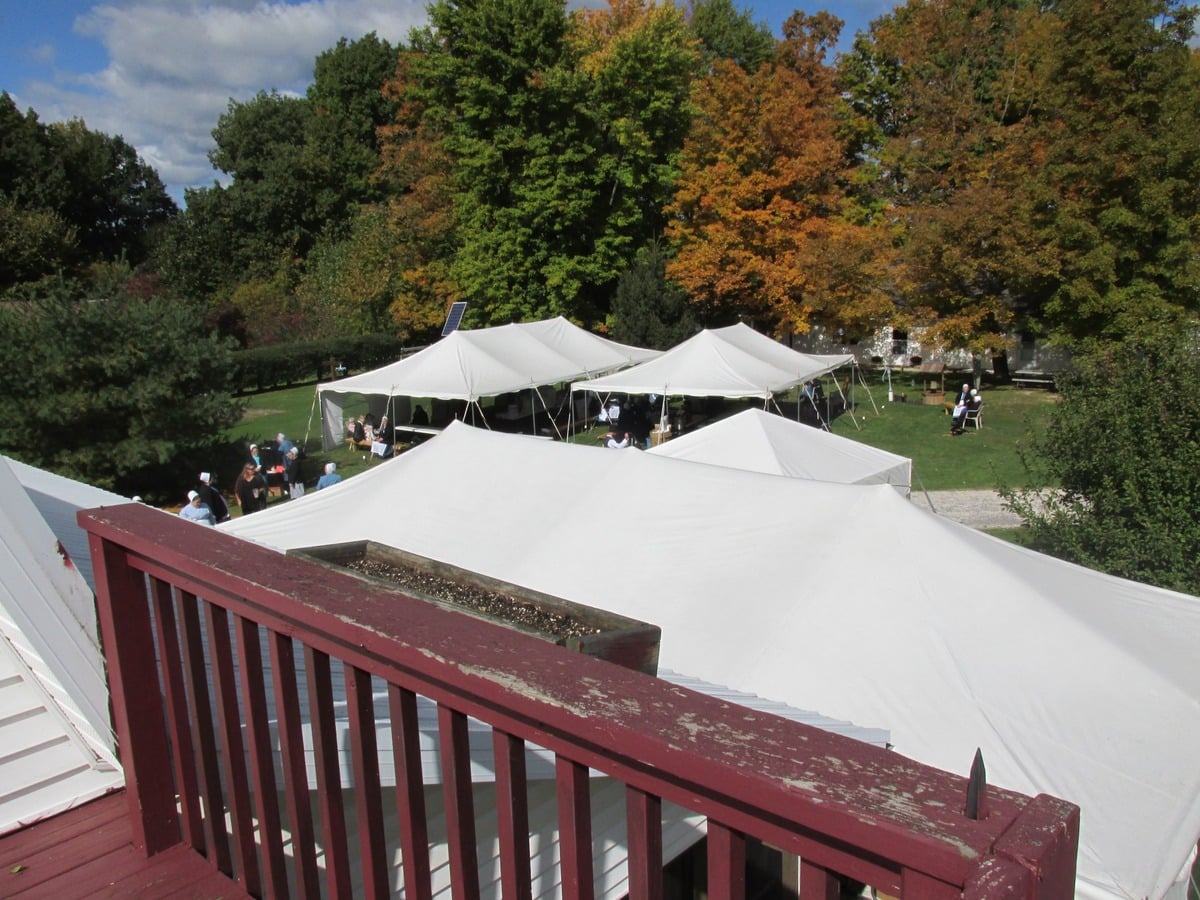 View from a deck of wedding tents and Amish guests on the lawn in autumn