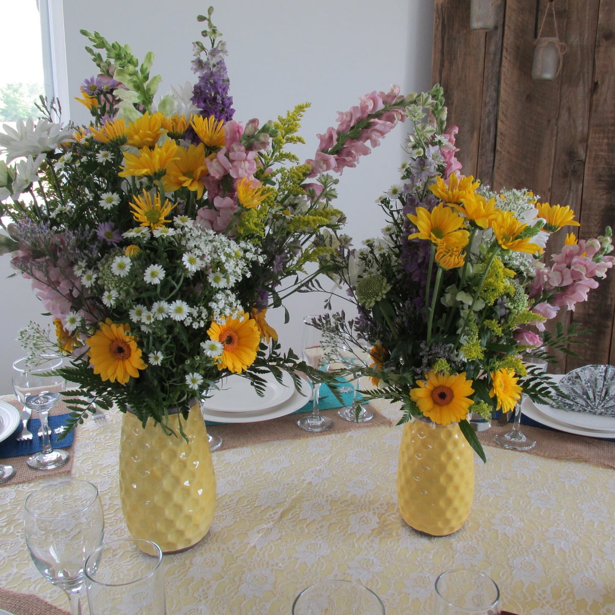 Wildflower arrangements in yellow vases on an Amish bridal table